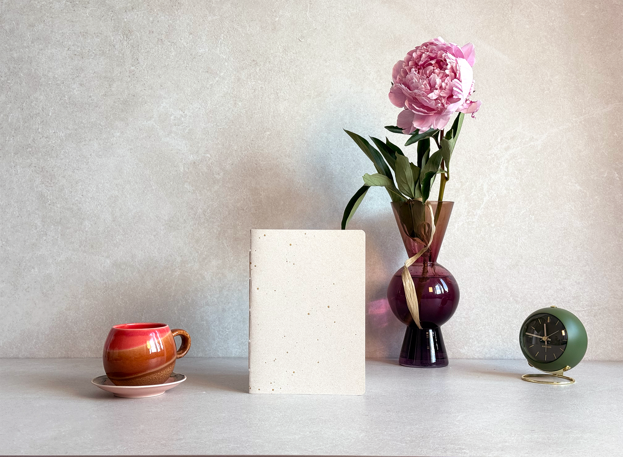 A handmade Lola Lima notebook next to a coffee cup and a peony
